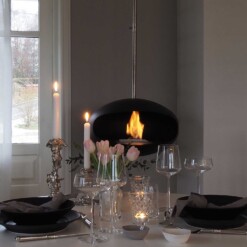 Cheminée bioéthanol suspendue Aeris de Cocoon Fires en noir mat avec suspension en inox dans une salle à manger
