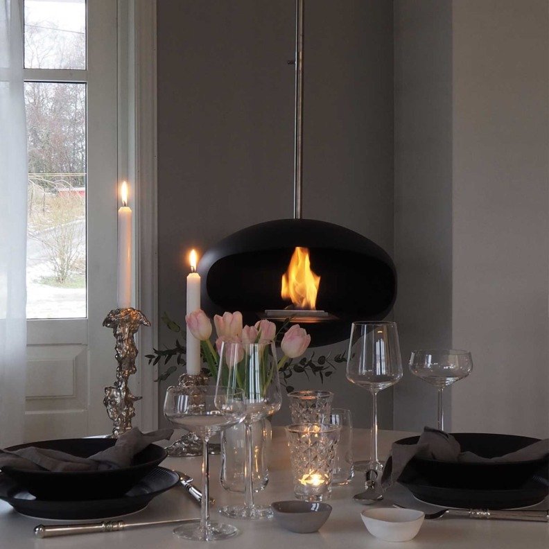 Cheminée bioéthanol suspendue Aeris de Cocoon Fires en noir mat avec suspension en inox dans une salle à manger