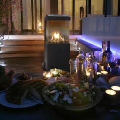 Cheminée à gaz The Buzz de Faber installée de nuit sur une terasse en extérieur