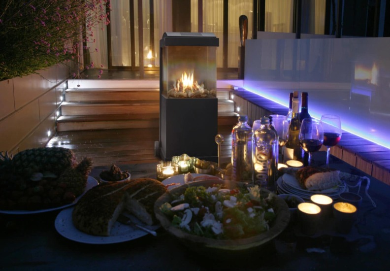 Cheminée à gaz The Buzz de Faber installée de nuit sur une terasse en extérieur