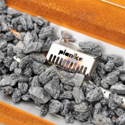 Gros plan sur la flamme et les décorations de le cheminée à gaz Galio utilisable en extérieur