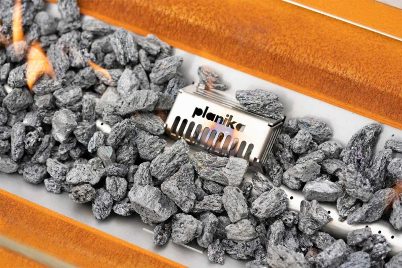 Gros plan sur la flamme et les décorations de le cheminée à gaz Galio utilisable en extérieur