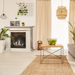 Cheminée Xaralyn Kos en parements de pierre crème au bioéthanol avec un fond brique et fausse plaque de fonte